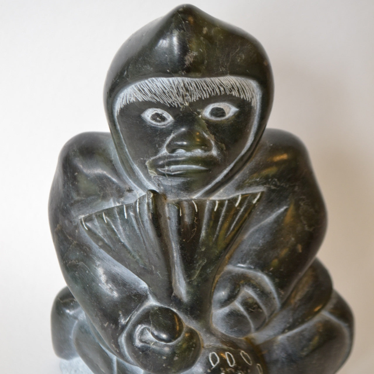 Inuit carving hunter with seal flippers in face