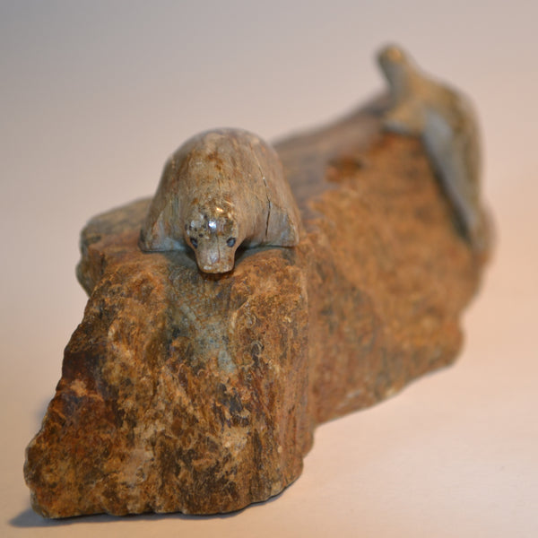 Inuit carving sea lions on cliff