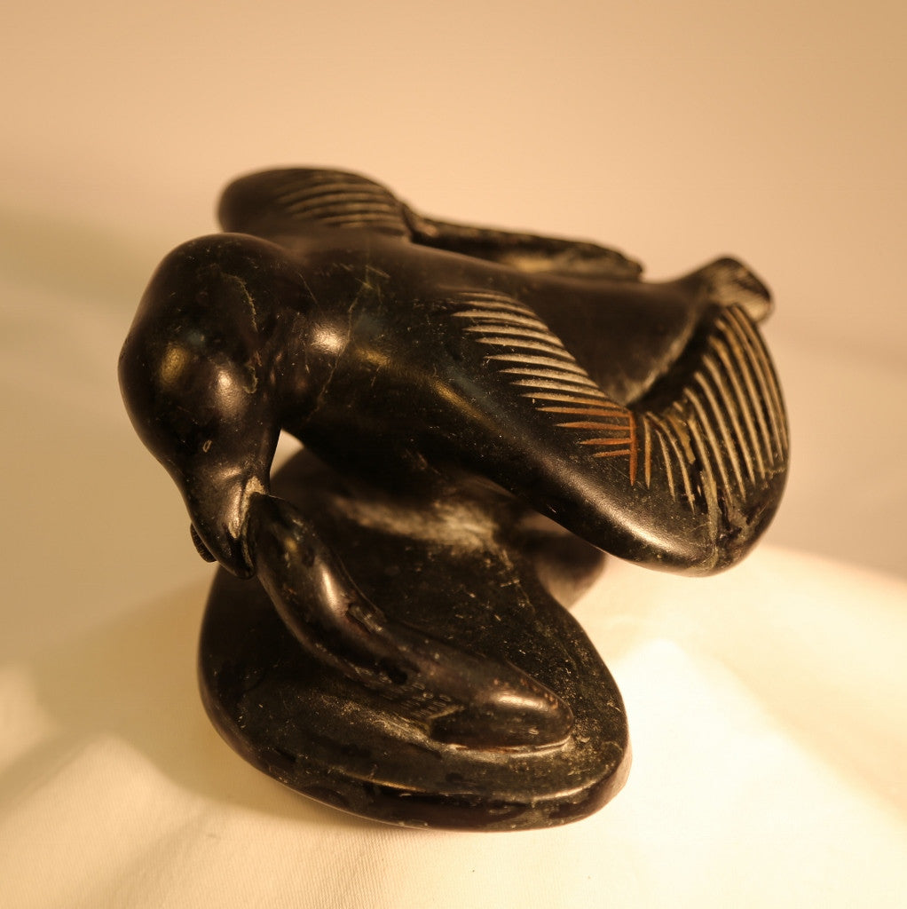 Winged bird catching fish carving